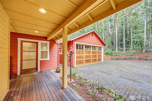 wooden terrace with an outdoor structure, a wooded view, and a garage