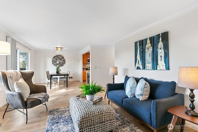 living area with visible vents, light wood-style flooring, baseboards, and ornamental molding