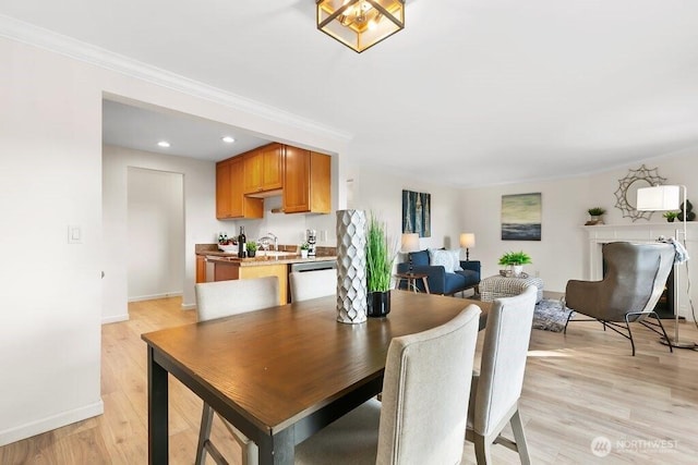 dining area featuring baseboards, light wood-style floors, and ornamental molding