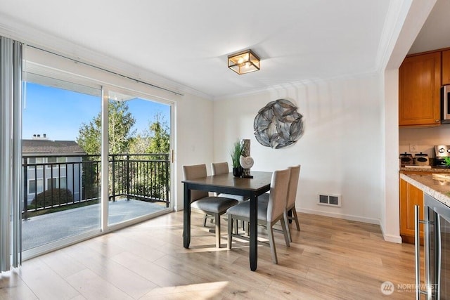 dining room with visible vents, wine cooler, light wood-style floors, crown molding, and baseboards