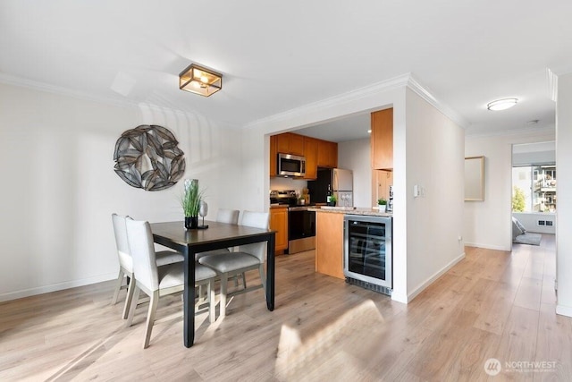 dining room featuring baseboards, wine cooler, light wood-style floors, and ornamental molding