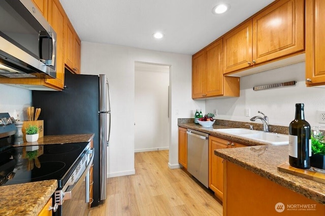 kitchen with recessed lighting, appliances with stainless steel finishes, light wood-style floors, brown cabinetry, and a sink