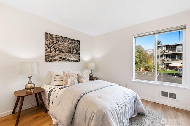 bedroom with visible vents, baseboards, and wood finished floors