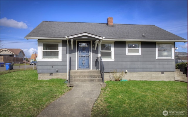 view of front of house featuring fence, a chimney, a front lawn, and a shingled roof