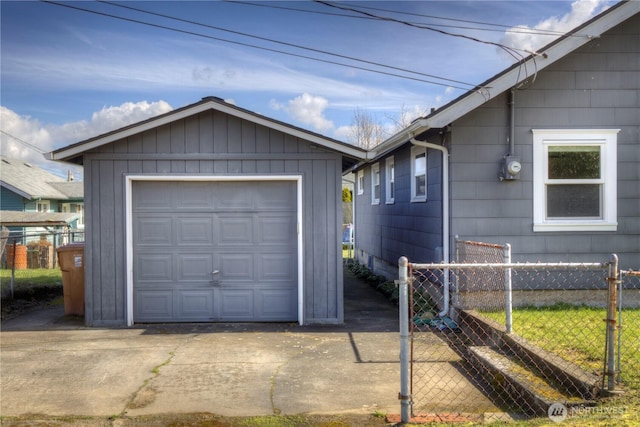 detached garage featuring concrete driveway and fence