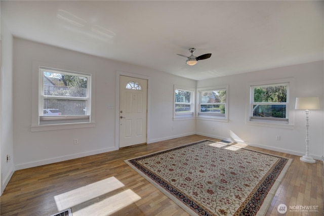 foyer entrance with baseboards, wood finished floors, and ceiling fan