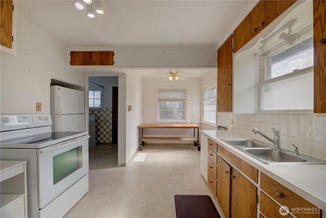 kitchen with a sink, tasteful backsplash, white appliances, light countertops, and light floors