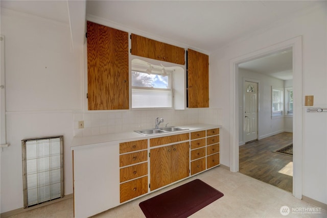 kitchen with light countertops, brown cabinets, backsplash, and a sink