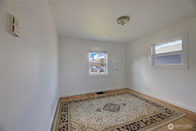 spare room with visible vents, baseboards, and wood finished floors