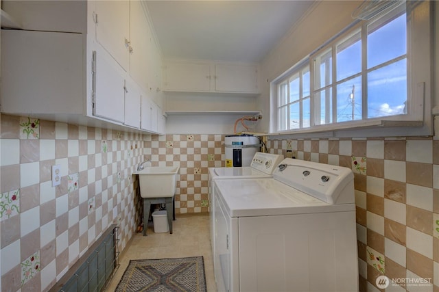 clothes washing area featuring cabinet space, water heater, a sink, washer and dryer, and tile walls