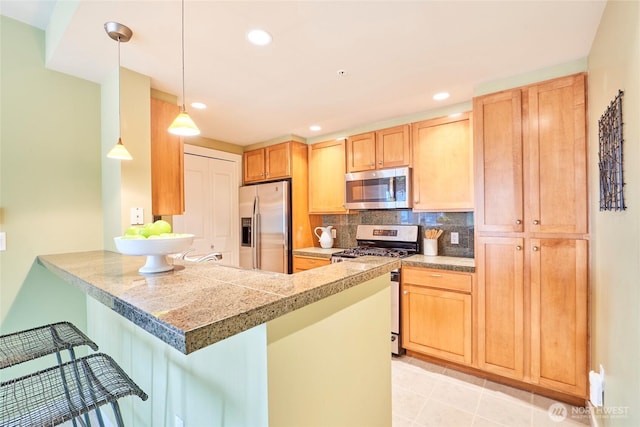 kitchen with a kitchen bar, tasteful backsplash, tile countertops, stainless steel appliances, and a peninsula