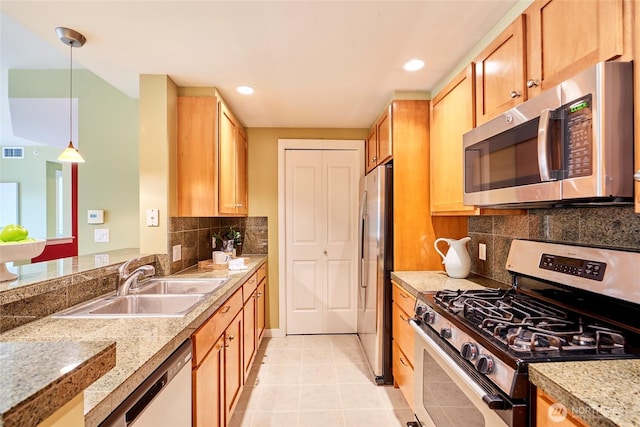 kitchen featuring pendant lighting, a sink, backsplash, appliances with stainless steel finishes, and light tile patterned floors