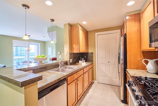 kitchen featuring tile counters, decorative light fixtures, decorative backsplash, appliances with stainless steel finishes, and a sink