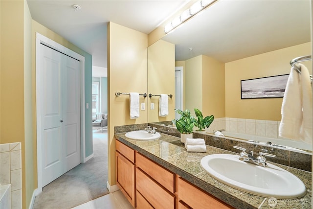 bathroom featuring a garden tub, double vanity, and a sink