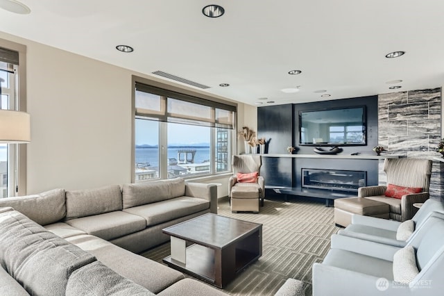 carpeted living area featuring visible vents and a glass covered fireplace