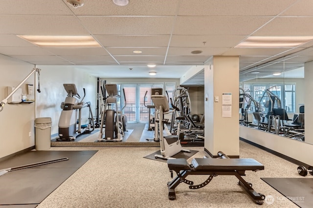 workout area featuring baseboards and a drop ceiling