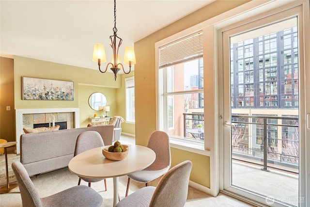 dining room featuring light colored carpet, a fireplace, baseboards, and a chandelier