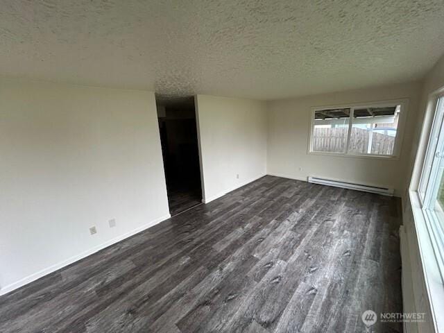 empty room with a textured ceiling, dark wood-type flooring, baseboards, and a baseboard radiator