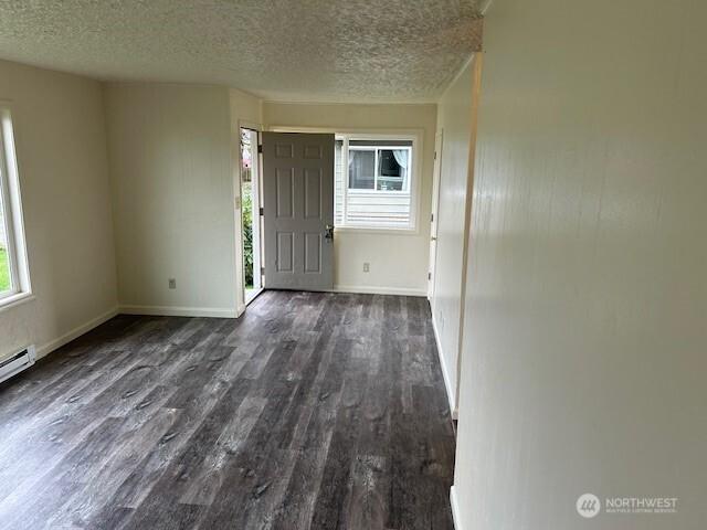 foyer featuring a textured ceiling, baseboards, and wood finished floors