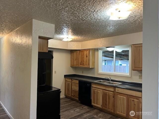 kitchen featuring dark countertops, black appliances, dark wood finished floors, a textured ceiling, and a sink