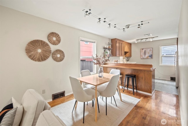 dining room featuring a wealth of natural light, visible vents, baseboards, and light wood finished floors