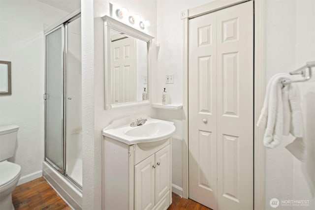 full bathroom with baseboards, toilet, a stall shower, wood finished floors, and vanity