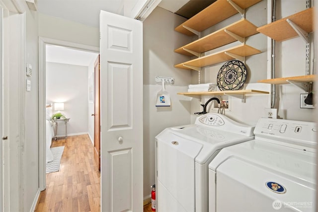 laundry room with light wood-type flooring, baseboards, separate washer and dryer, and laundry area