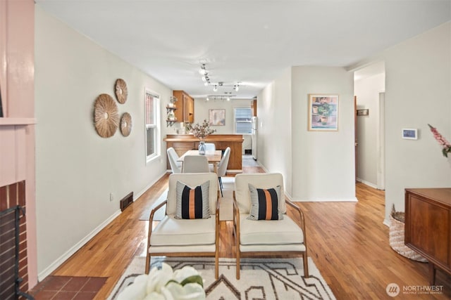 dining area with visible vents, a fireplace, baseboards, and wood finished floors