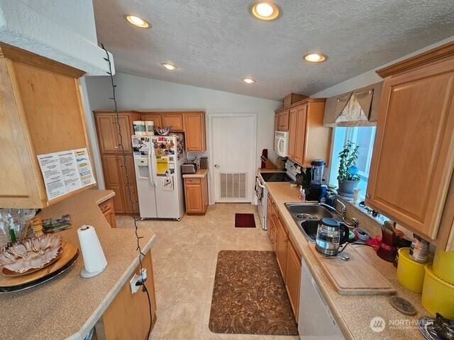 kitchen featuring white appliances, visible vents, a sink, vaulted ceiling, and light countertops