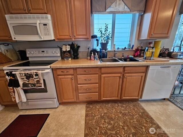 kitchen with a sink, white appliances, tile countertops, and light tile patterned floors