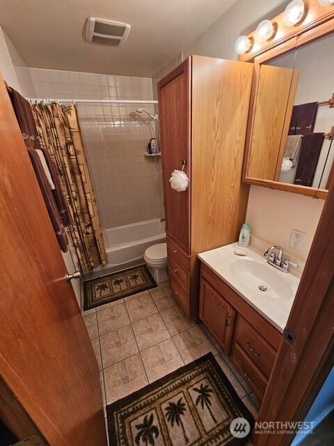 bathroom featuring visible vents, toilet, vanity, and shower / tub combo