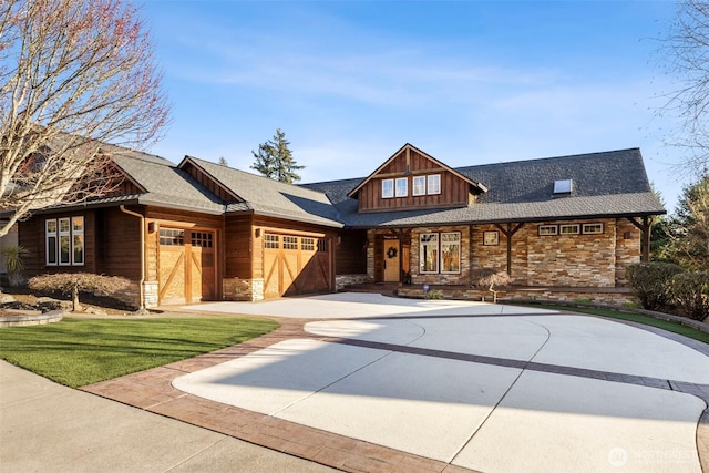 view of front of property featuring a front yard, a garage, stone siding, and driveway