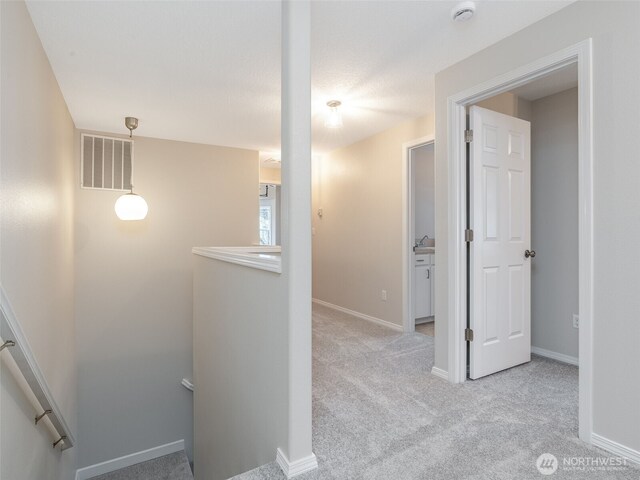 corridor featuring visible vents, an upstairs landing, carpet, and baseboards