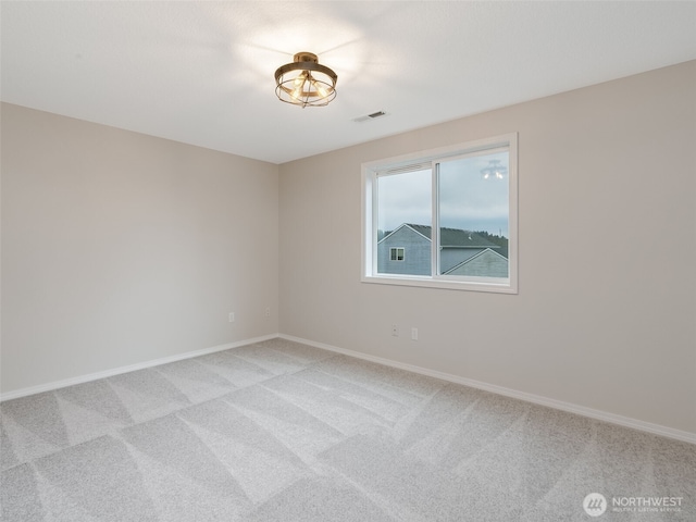 spare room featuring light colored carpet, visible vents, and baseboards