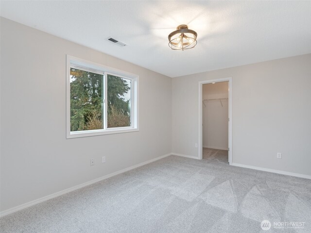 unfurnished bedroom featuring visible vents, baseboards, a spacious closet, and carpet flooring