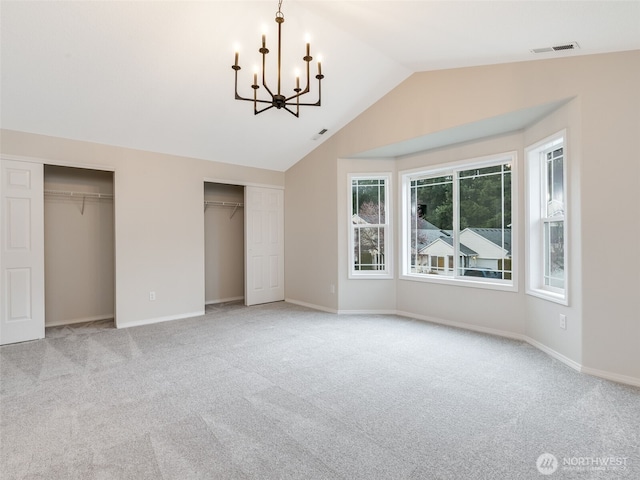 unfurnished bedroom with visible vents, multiple closets, an inviting chandelier, lofted ceiling, and light colored carpet