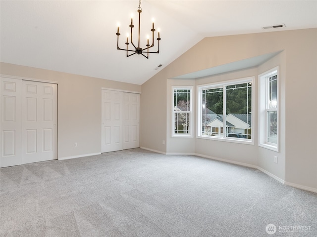 interior space featuring visible vents, baseboards, lofted ceiling, carpet flooring, and a notable chandelier