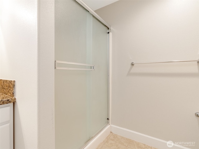 bathroom featuring vanity, a shower stall, baseboards, and tile patterned floors