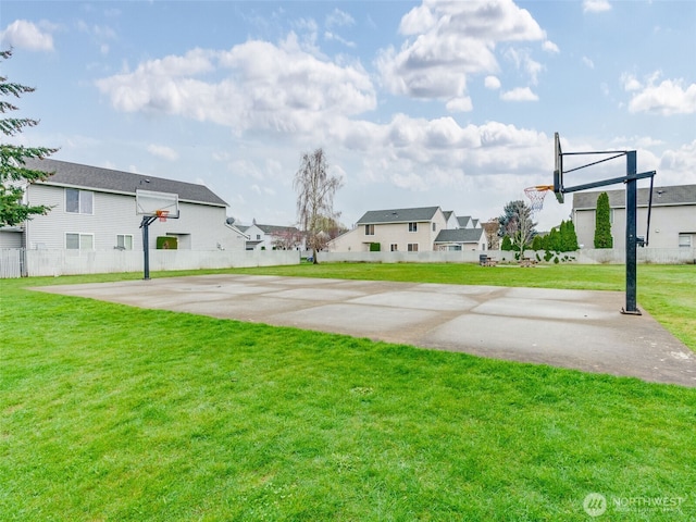 view of yard featuring basketball hoop, fence, and a residential view