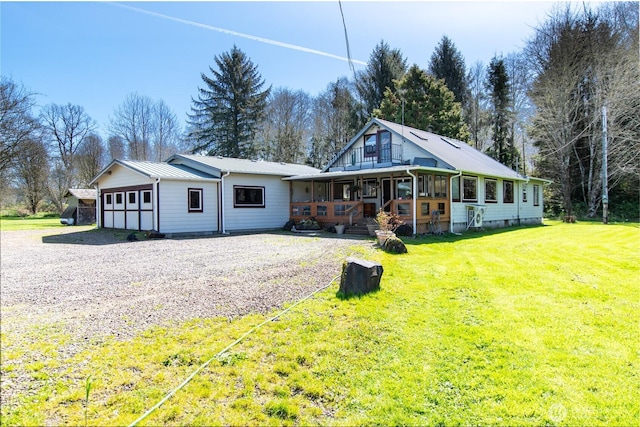 view of front facade featuring a front yard, driveway, an attached garage, covered porch, and metal roof