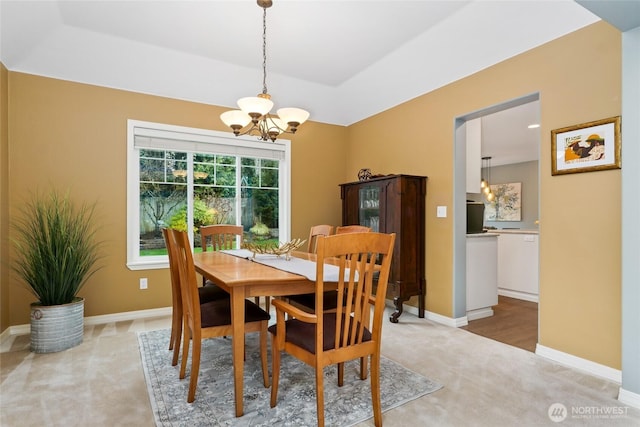 dining room featuring a notable chandelier, light colored carpet, and baseboards