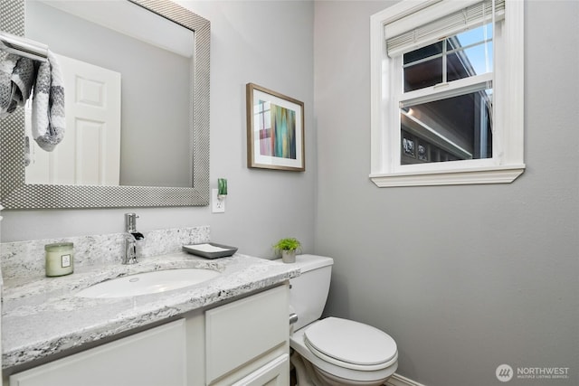 bathroom featuring toilet, vanity, and baseboards