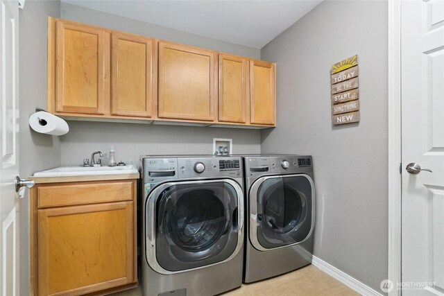 laundry room with washing machine and dryer, cabinet space, baseboards, and a sink