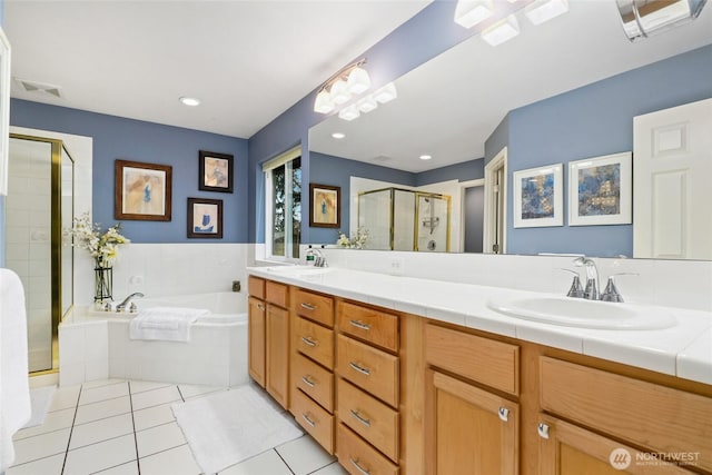 full bathroom featuring double vanity, a stall shower, a sink, tile patterned flooring, and a garden tub