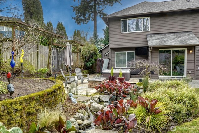 back of house featuring a patio area, a shingled roof, a hot tub, and fence