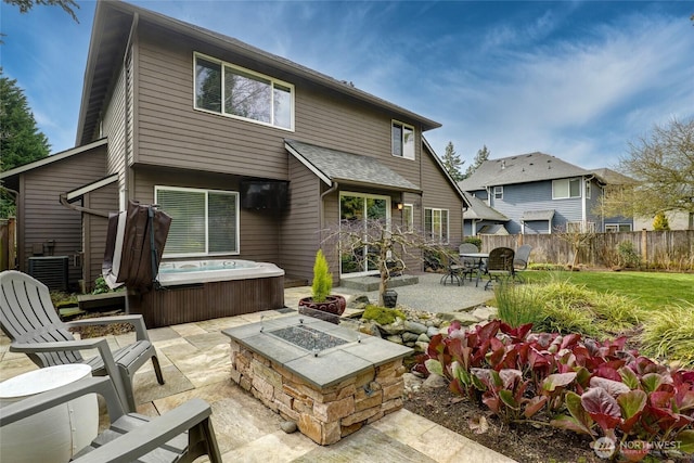 back of property featuring central AC, fence, a patio area, a fire pit, and a hot tub