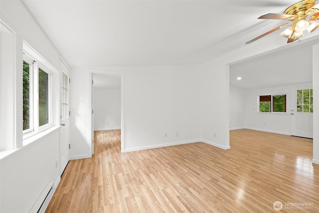 unfurnished room featuring a baseboard heating unit, a ceiling fan, baseboards, and light wood finished floors