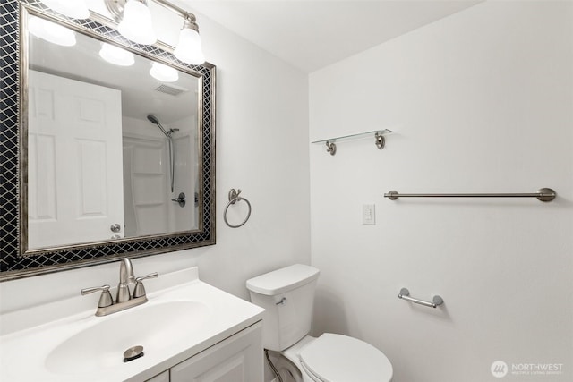 bathroom with vanity, toilet, a shower, and visible vents