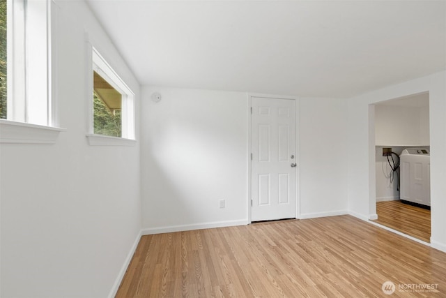 spare room featuring washer / clothes dryer, light wood-type flooring, and baseboards