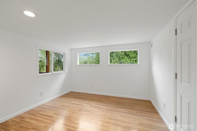 unfurnished room with light wood-type flooring and baseboards